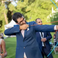 Novio con arco y flecha, parte de los juegos de bodas. La novia sonríe a su lado.