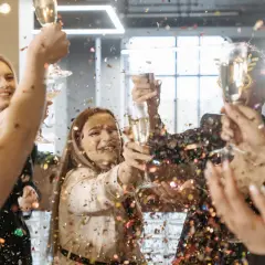 Gente celebrando un aniversario de empresas con confeti y copas de champán.