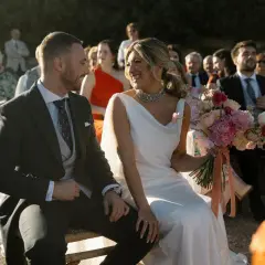 Novios sonrientes en su **matrimonio express**. Ella, radiante con vestido blanco y ramo de flores. Él, elegante de traje oscuro.