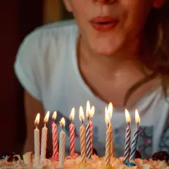 Niña soplando velas en un pastel. ¡Una idea genial para celebrar qué hacer en tu cumpleaños!