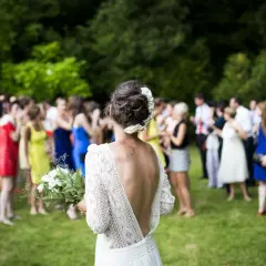 Novia con ramo, rodeada de invitados en los preparativos de boda.