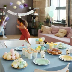 Niños corriendo en una fiesta de cumpleaños, con mesa llena de dulces y pastel. ¡Ideas de qué hacer en una fiesta!