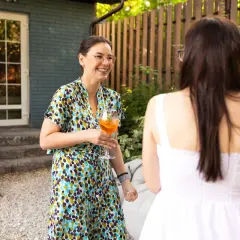Mujeres riendo y brindando en una fiesta temática al aire libre.