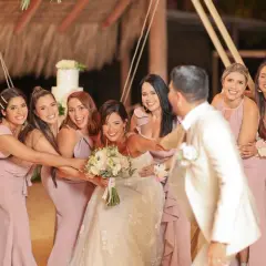 La novia y sus damas de honor ríen juntas, rodeando a la feliz pareja en un día especial.