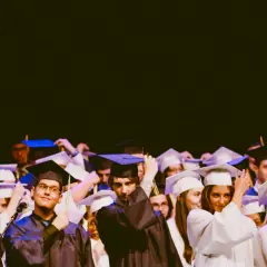 Estudiantes celebran su graduación universitaria, ajustándose togas y birretes.