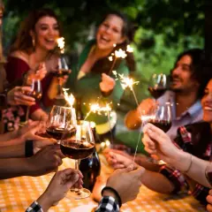 Amigos celebran un cumpleaños con vino y bengalas, disfrutando de momentos especiales. ¡Ideas geniales de cosas para hacer en tu cumpleaños con amigos!