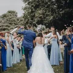 Novios celebran con confeti. El dresscode que es, se ve en los vestidos azules de las damas y trajes oscuros de los caballeros.