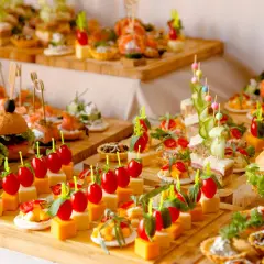 Variedad de aperitivos para bodas: mini hamburguesas, canapés de salmón, brochetas de tomate y queso, y tartas saladas. ¡Un festín visual!