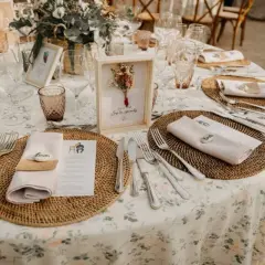 Mesa de boda con manteles florales, vajilla y centros de mesa rústicos.