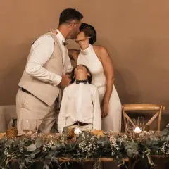 Una pareja se besa tiernamente mientras su hijo mira al cielo, celebrando bodas de plata, oro y platino.