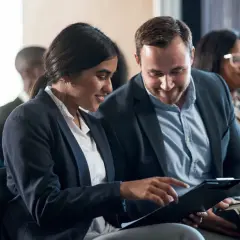 Pareja revisa documentos en una convención de empresa.