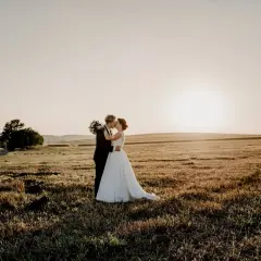 Novios besándose en un campo dorado al atardecer, un hermoso escenario para bodas en mayo.