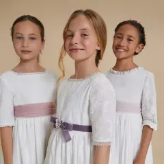 Tres niñas con vestidos blancos de comunión, cinturones rosas y morados. Ideas para sorprender a una niña en su comunión.