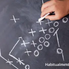 Mano con tiza dibuja jugada en pizarra, creando estrategia a pesar de las adversidades.