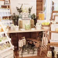 Un candy bar rústico con dulces, botellas de agua y un cartel "Mesa Dulce".