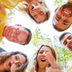 Un grupo de personas sonríe y señala hacia abajo, fomentando el espíritu de equipo. ¡Perfecto para dinamicas de grupo para empresas!