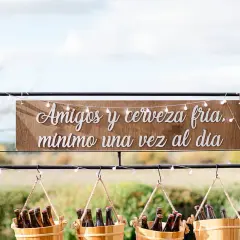 Decoración barra libre boda: letrero "Amigos y cerveza fría, mínimo una vez al día" sobre cubos de cerveza.