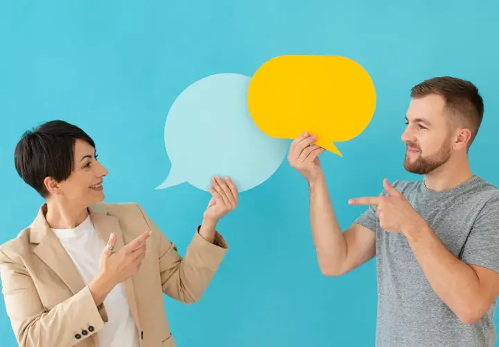 Hombre y mujer con bocadillos de diálogo, discutiendo ideas. Sonrisas y gestos sugieren técnicas para no entrar al trapo en una conversación.