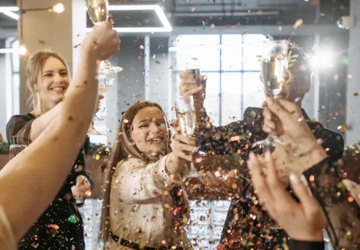 Gente celebrando un aniversario de empresas con confeti y copas de champán.