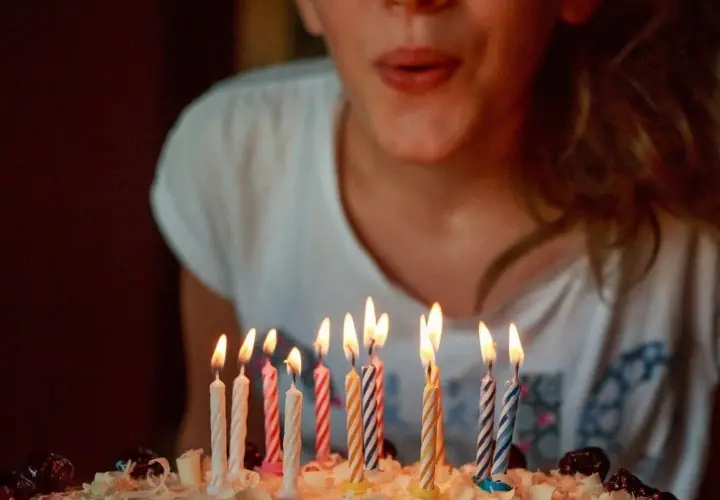 Niña soplando velas en un pastel. ¡Una idea genial para celebrar qué hacer en tu cumpleaños!