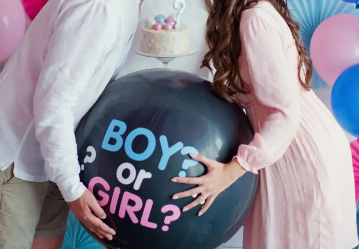 Pareja celebra un gender reveal, con un globo negro que pregunta "BOY or GIRL?".