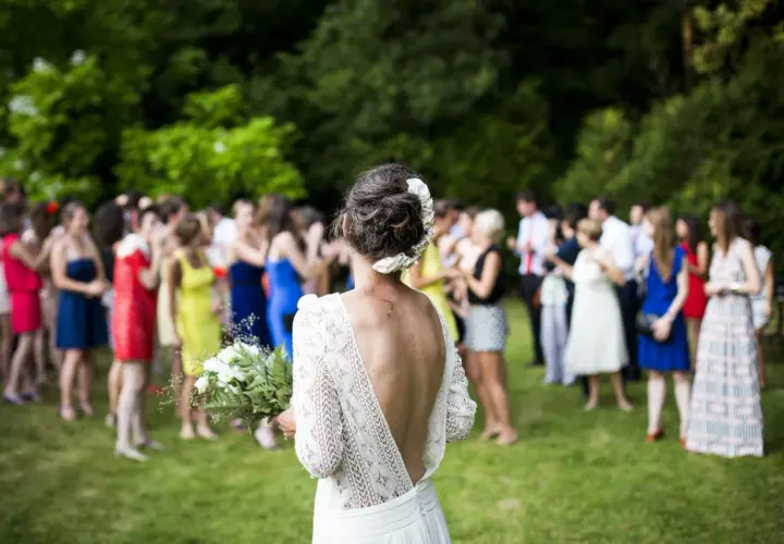 Novia con ramo, rodeada de invitados en los preparativos de boda.