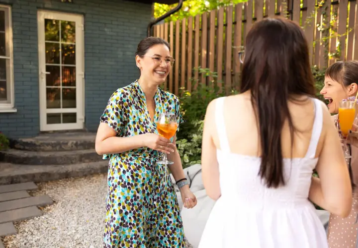 Mujeres riendo y brindando en una fiesta temática al aire libre.