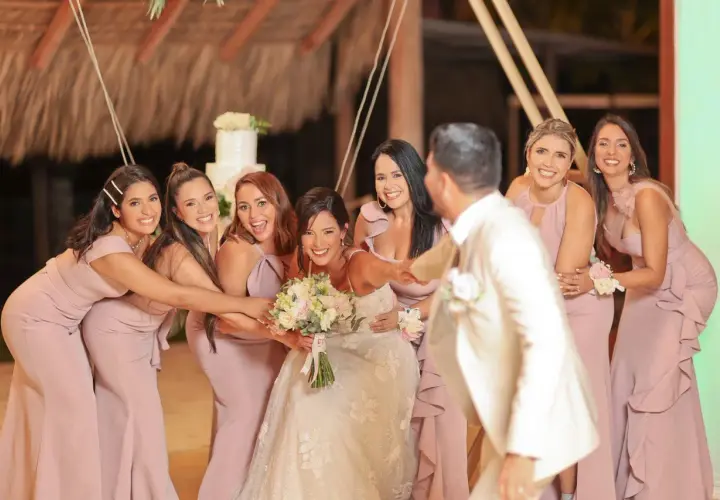La novia y sus damas de honor ríen juntas, rodeando a la feliz pareja en un día especial.