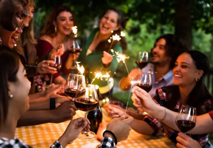 Amigos celebran un cumpleaños con vino y bengalas, disfrutando de momentos especiales. ¡Ideas geniales de cosas para hacer en tu cumpleaños con amigos!
