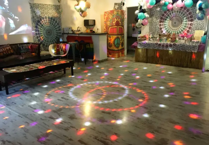 Un salón decorado con estilo hippie para unas **fiestas de cumpleaños de adultos divertidas**. Luces de discoteca proyectan círculos de colores sobre el suelo.