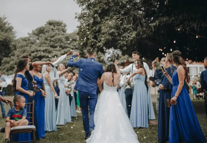 Novios celebran con confeti. El dresscode que es, se ve en los vestidos azules de las damas y trajes oscuros de los caballeros.
