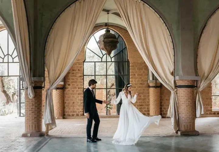 Novios bailan en un salón con arcos y cortinas, celebrando que las bodas son a los 10 años.