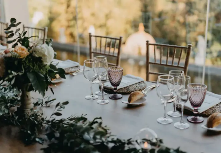 Mesa de boda romántica vintage con flores, copas de cristal y panecillos.