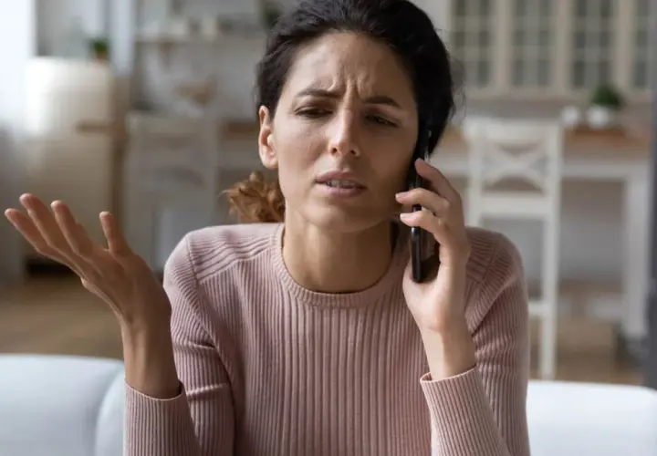 Mujer con expresión de fastidio habla por teléfono, parece una persona que se queja de todo.