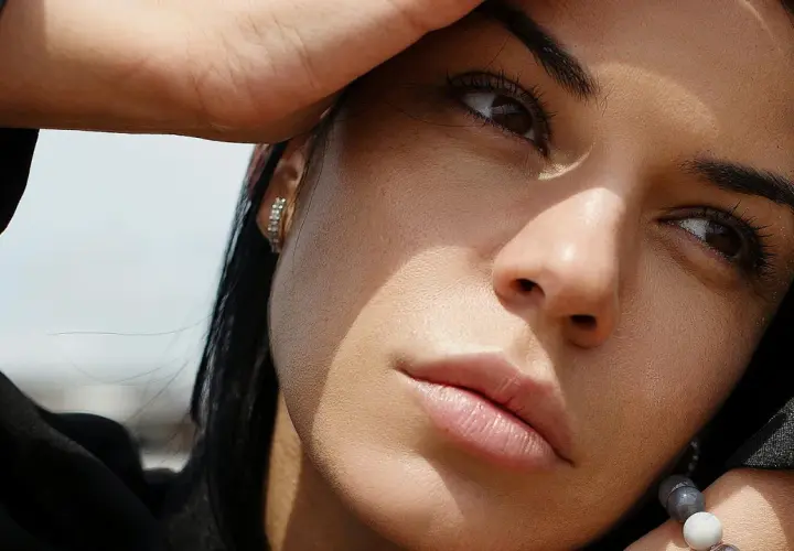 Primer plano de una mujer pensativa, con la mano en la frente, como si estuviera dándole vueltas a las cosas, significado en su mirada.