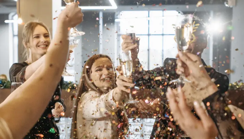 Gente celebrando un aniversario de empresas con confeti y copas de champán.