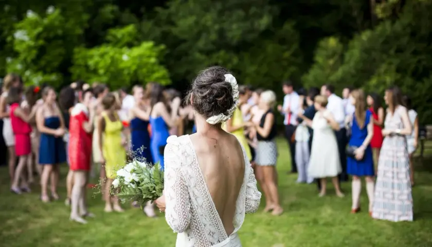 Novia con ramo, rodeada de invitados en los preparativos de boda.