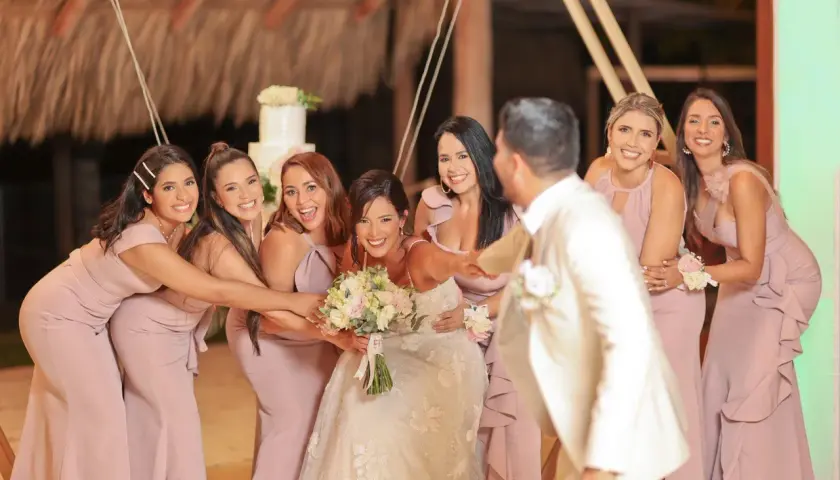 La novia y sus damas de honor ríen juntas, rodeando a la feliz pareja en un día especial.