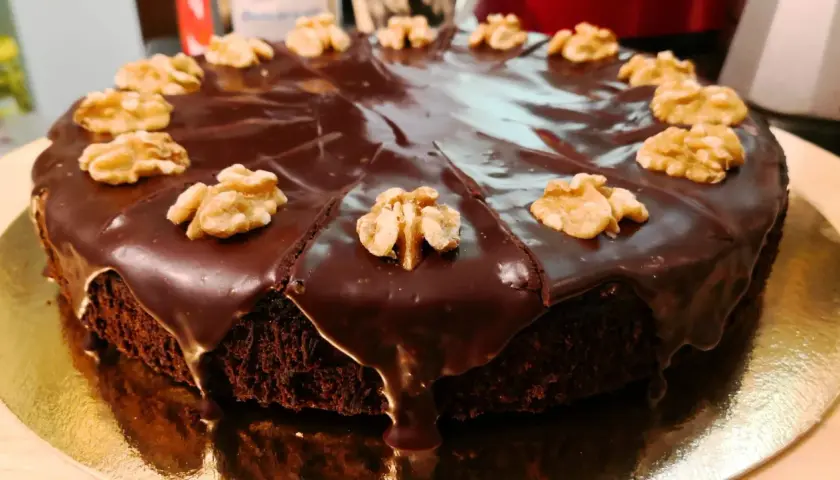 Pastel de chocolate cubierto de glaseado brillante y nueces, perfecto para ideas de cumpleaños de 16 años.