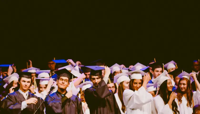 Estudiantes celebran su graduación universitaria, ajustándose togas y birretes.