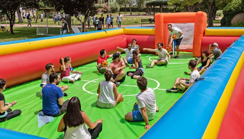 Gente disfrutando de un día familiar en empresas, sentados en un campo de fútbol inflable, riendo y jugando.