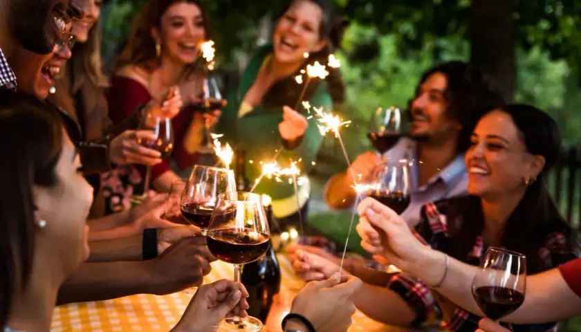 Amigos celebran un cumpleaños con vino y bengalas, disfrutando de momentos especiales. ¡Ideas geniales de cosas para hacer en tu cumpleaños con amigos!