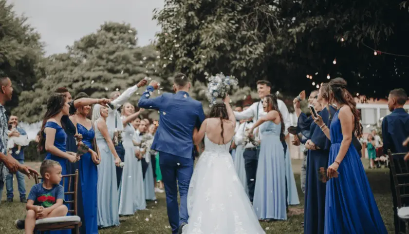 Novios celebran con confeti. El dresscode que es, se ve en los vestidos azules de las damas y trajes oscuros de los caballeros.