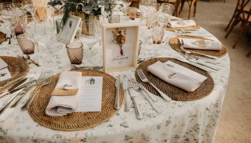 Mesa de boda con manteles florales, vajilla y centros de mesa rústicos.