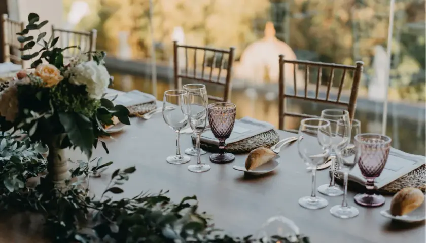 Mesa de boda romántica vintage con flores, copas de cristal y panecillos.