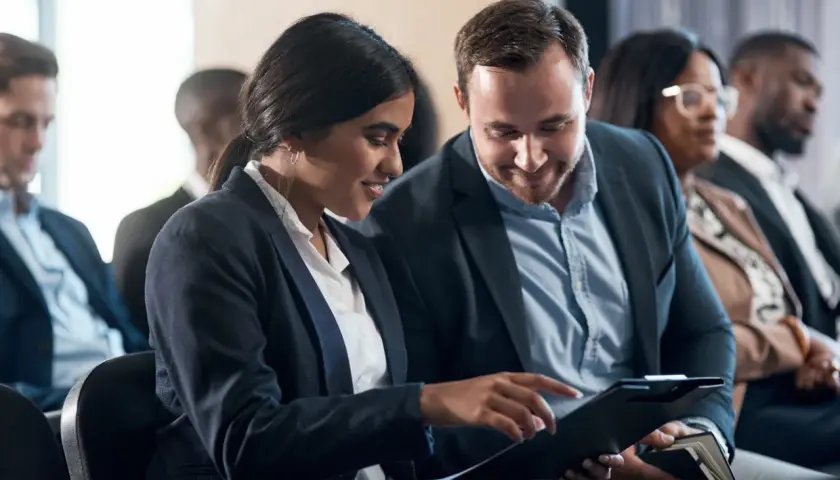 Pareja revisa documentos en una convención de empresa.