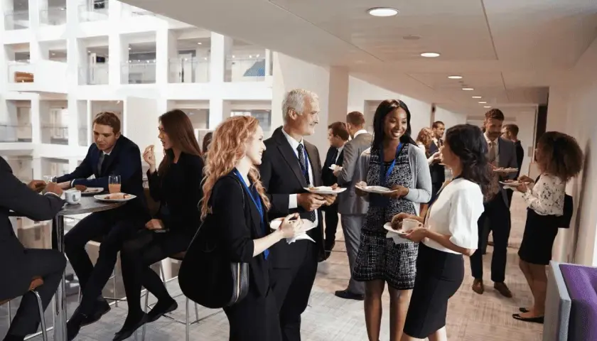 Profesionales conversan y disfrutan de un cóctel en un evento corporativo. Ejemplos de networking y colaboración.