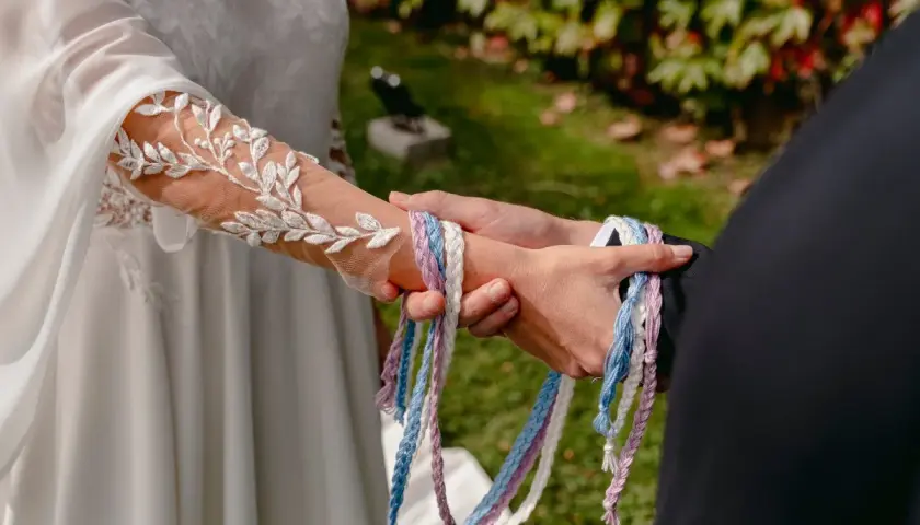 Manos unidas por cintas de colores, un hermoso simbolo matrimonio.