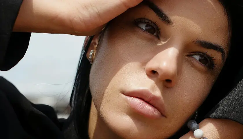 Primer plano de una mujer pensativa, con la mano en la frente, como si estuviera dándole vueltas a las cosas, significado en su mirada.