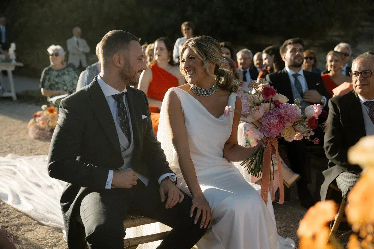Novios sonrientes en su **matrimonio express**. Ella, radiante con vestido blanco y ramo de flores. Él, elegante de traje oscuro.